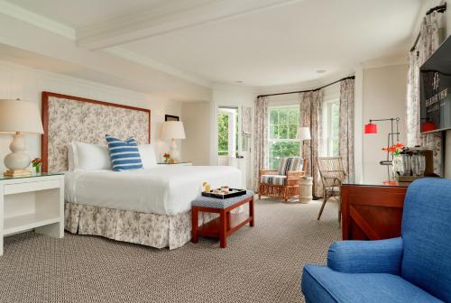 a bedroom with a bed and a blue chair at Harbor View Hotel in Edgartown
