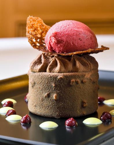a piece of chocolate cake with a pink donut on top at Hostellerie Schwendi in Kientzheim