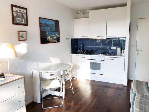une cuisine avec des armoires blanches et une table et des chaises dans l'établissement B17 Studio avec vue imprenable, à Arcachon