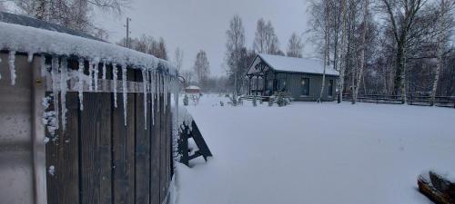 a house covered in snow next to a fence at Brīvdienu māja ar Saunu in Saulkrasti