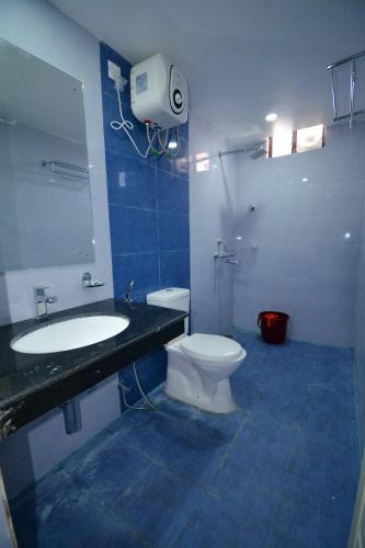 a bathroom with a toilet and a sink and a mirror at HOTEL CORAL INN -HCI in Port Blair