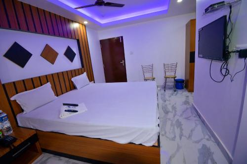 a bedroom with a white bed and a tv at HOTEL CORAL INN -HCI in Port Blair
