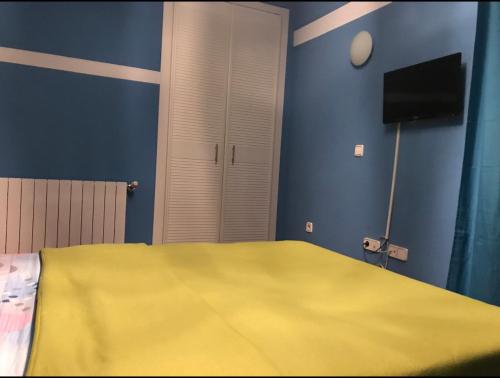 a bedroom with a yellow bed and a television at Chalé Barajas Escala in Madrid