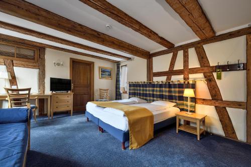 a bedroom with a bed and a desk and a tv at Hostellerie Schwendi in Kientzheim