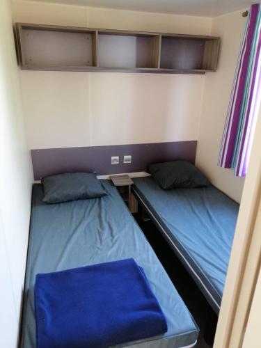 Cette petite chambre comprend deux lits et un bureau. dans l'établissement Mobil Home climatisé Camping Novella, à Port-la-Nouvelle
