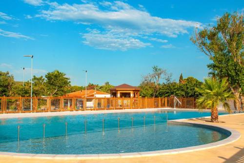 uma grande piscina com uma casa ao fundo em Mobil Home climatisé Camping Novella em Port-la-Nouvelle