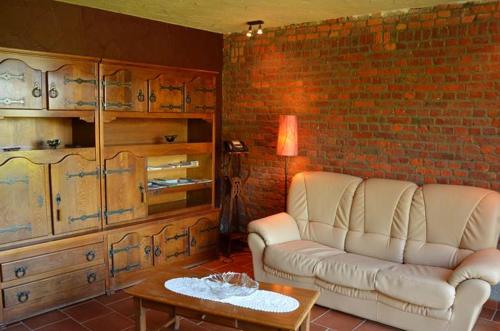 a living room with a white couch and a brick wall at Gîtes Ferme de la Barrière in Chimay