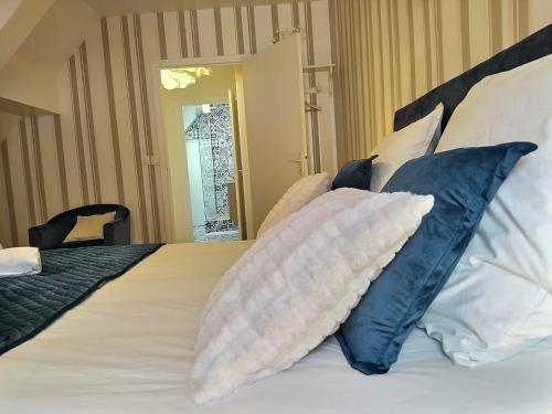 Una cama con almohadas azules y blancas. en Chambre d'hôtes de Verdigné Piscine Parking Wifi, en Le Mans