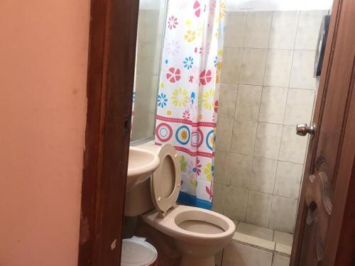 y baño con aseo y cortina de ducha. en Hostal Luz Wilson, en Quito