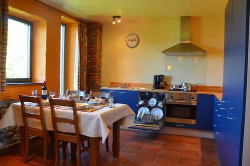 a kitchen with a table and a stove and a table and chairs at Gîtes Ferme de la Barrière in Chimay