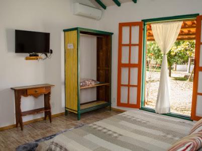 sala de estar con TV, mesa y puerta en Pouso dos Querubins en Tiradentes