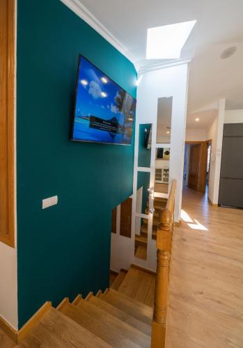 a living room with a blue wall with a tv on it at ATICO CAPRICHOS ARANDA in Aranda de Duero