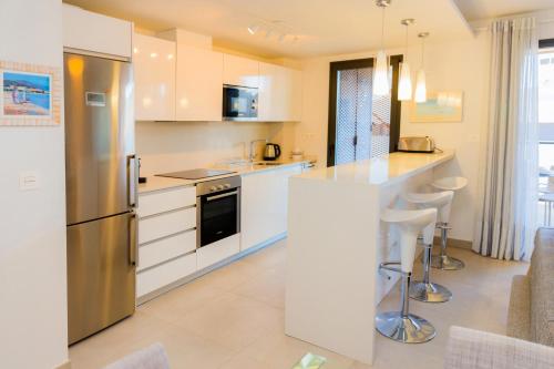 a kitchen with white cabinets and a stainless steel refrigerator at Arenal Dream Penthouse I Javea Arenal by Rock Rentals in Jávea
