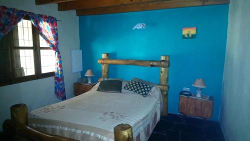 1 dormitorio con cama de madera y paredes azules en Finca La Casa Amarilla en San Rafael