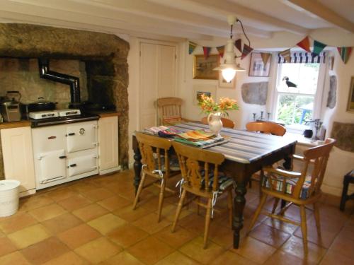 een keuken met een houten tafel en stoelen bij Beautiful Nancherrow Cottage in St Just