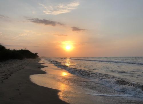 a sunset on a beach with the ocean at Territorio Magico Dibulla in Dibulla