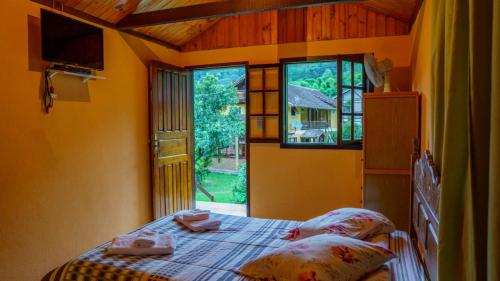 1 dormitorio con cama y ventana grande en Pousada Vale da Represa, en Visconde De Maua
