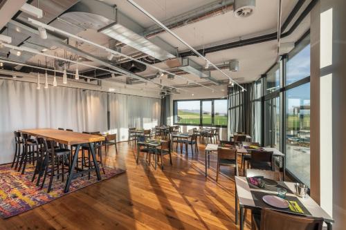 a dining room with tables and chairs and large windows at Macardo Premium B&B in Bissegg