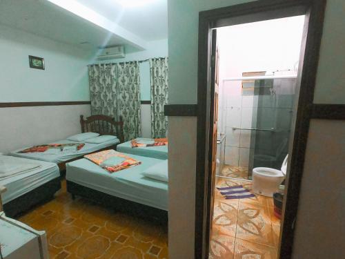 a small room with two beds and a shower at Guajará Palace Hotel in Porto Velho