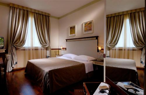 a hotel room with two beds and two windows at Zanhotel Centergross in Bentivoglio
