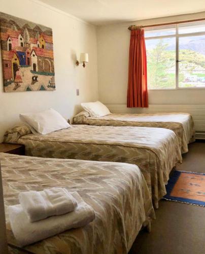 a hotel room with three beds and a window at Hotel Las Vicuñas in Putre