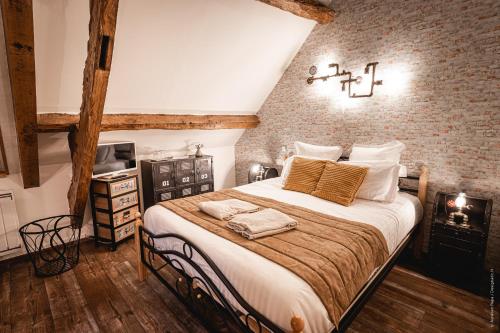 - une chambre avec un grand lit et un mur en briques dans l'établissement La Brocherie, à Magny-le-Désert
