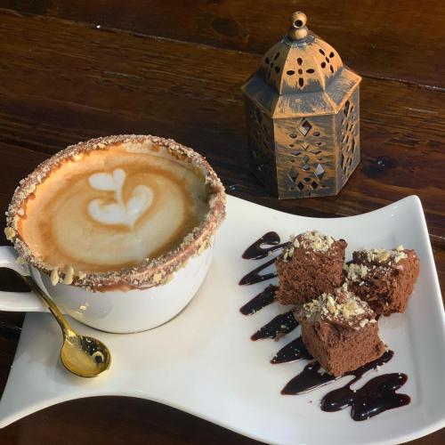 a cup of coffee and a piece of cake on a plate at Boutique Hotel Belgica in Ponce