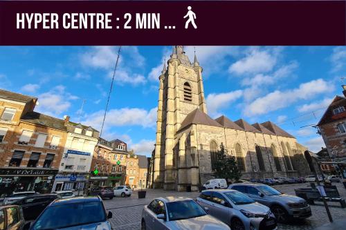 eine große Kirche mit einem Uhrturm in einer Stadt in der Unterkunft le cocon avesnois in Avesnes-sur-Helpe