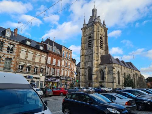 eine alte Kirche mit einem Uhrturm auf einem Parkplatz in der Unterkunft le cocon avesnois in Avesnes-sur-Helpe