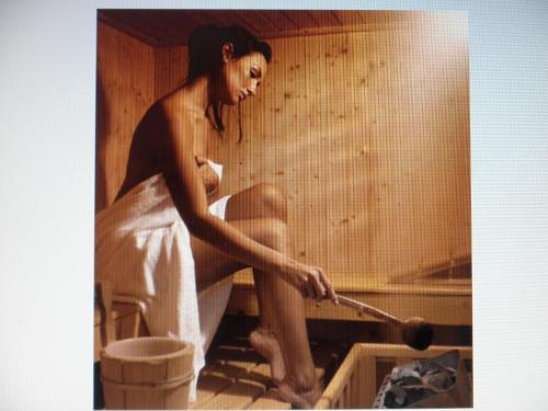a woman sitting in a sauna holding a wand at Park Hotel in Castrocaro Terme