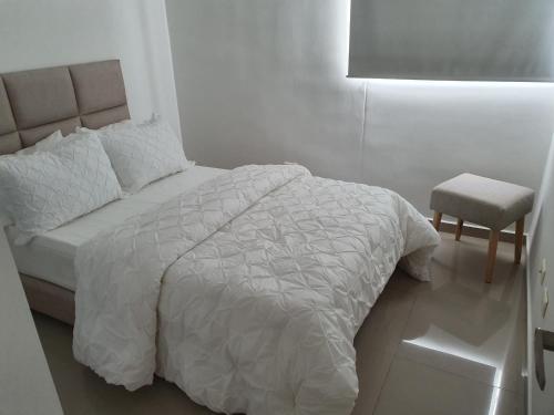a white bedroom with a bed and a chair at Excelente Apartamento Completo, en la mejor zona in Cúcuta