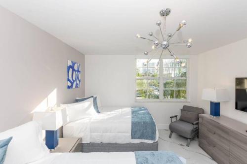 a white bedroom with two beds and a chandelier at Yacht Club at Aventura Lux 2 Bed 2 Bath Brand New 2021 in Aventura