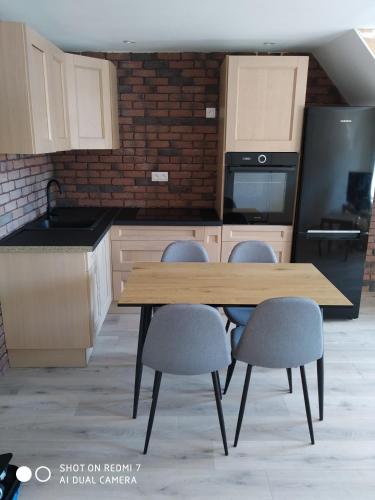 a kitchen with a wooden table and four chairs at Les Glycines in Guewenheim