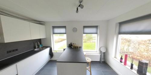 a kitchen with white cabinets and a black counter top at Topsleep Villa Lathum in Lathum