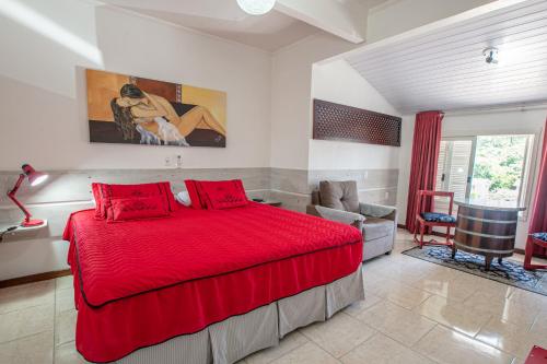 a bedroom with a red bed and a chair at Hotel Pousada Casa Tasca in Bento Gonçalves