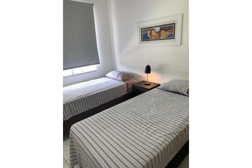 2 camas en una habitación pequeña con ventana en Loft Central Master Collection, en Passo Fundo