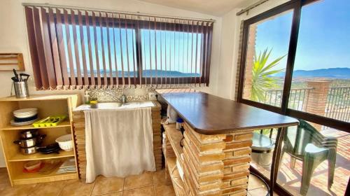 a kitchen with a table and a large window at Country Sun Apartments in Casarabonela