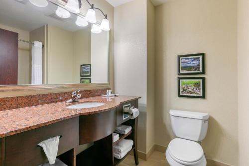 a bathroom with a toilet and a sink with a mirror at Comfort Suites in Forrest City