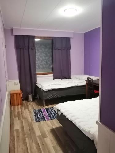 two beds in a room with purple walls at Köpsintie 4 B in Pyhäsalmi