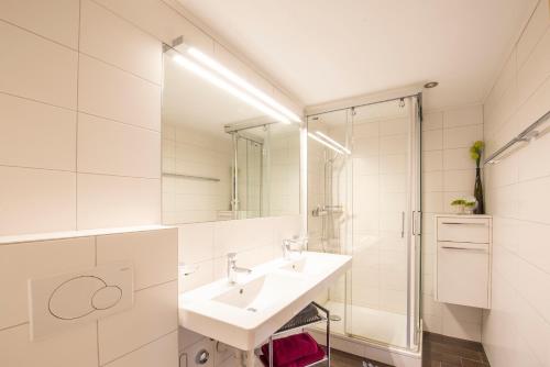 a white bathroom with a sink and a shower at Moräna in Bettmeralp