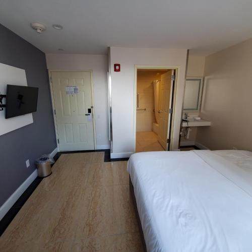 a bedroom with a white bed and a hallway at Mayfair Inn and Suites in Queens