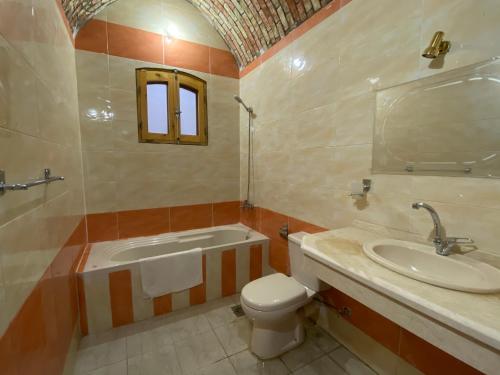 a bathroom with a tub and a toilet and a sink at Elsanosy Family Guest House - Luxor in Luxor