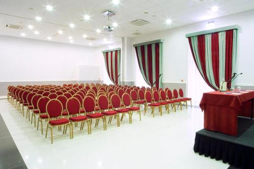 a large room with red chairs and a podium in it at Zanhotel Centergross in Bentivoglio