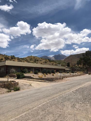 an empty road in front of a building with mountains at Hotel Las Vicuñas in Putre