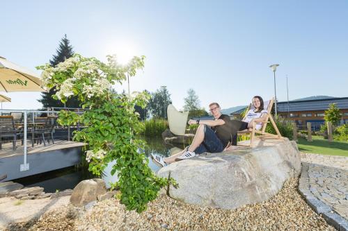 two people sitting in chairs on a rock by the water at Rekreační domek Kobylnice Lipno in Lipno nad Vltavou