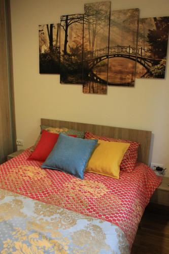 ein Schlafzimmer mit einem Bett mit vier Gemälden an der Wand in der Unterkunft Apartman Harmonija in Zlatibor