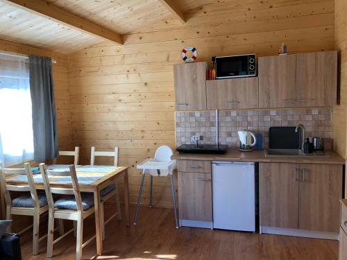 a kitchen and dining room with a table and a microwave at WAKACYJNE ZAGAJE in Sarbinowo