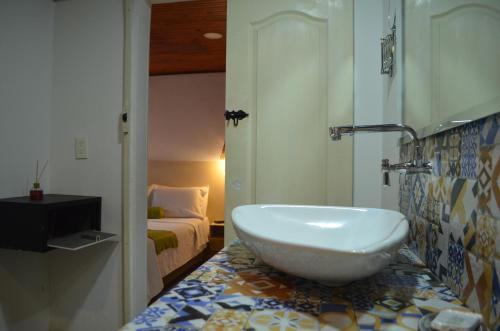 a bathroom with a sink and a bedroom with a bed at Aromarte Finca Hotel in Filandia