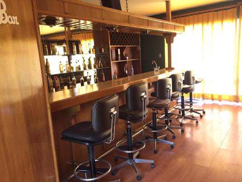 a bar with a row of black bar stools at Hotel Las Vicuñas in Putre