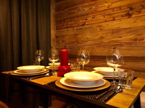 a table with plates and glasses and a red candle at Central Apart Chalet in Breuil-Cervinia